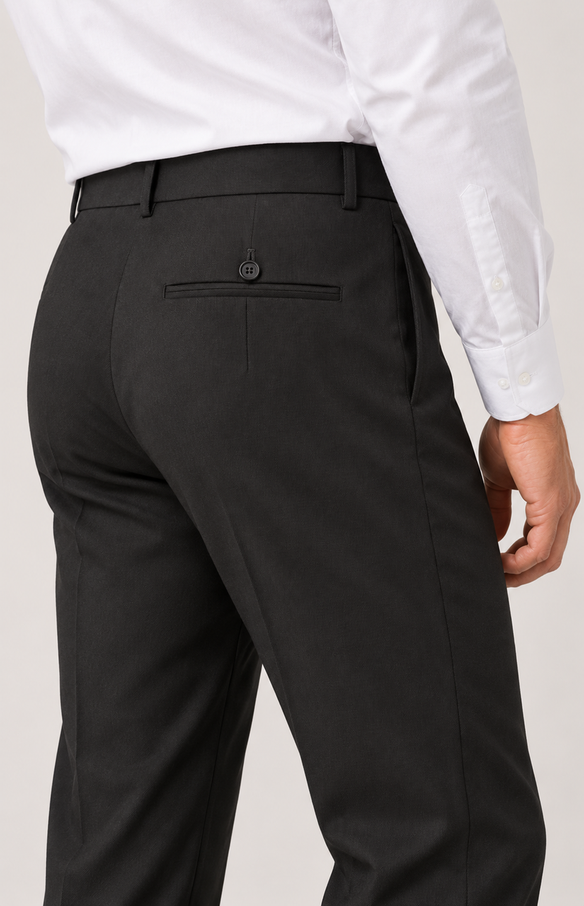 On-model close view of the black 8228 trouser waistband, belt loops and buttoned back welt pocket.
