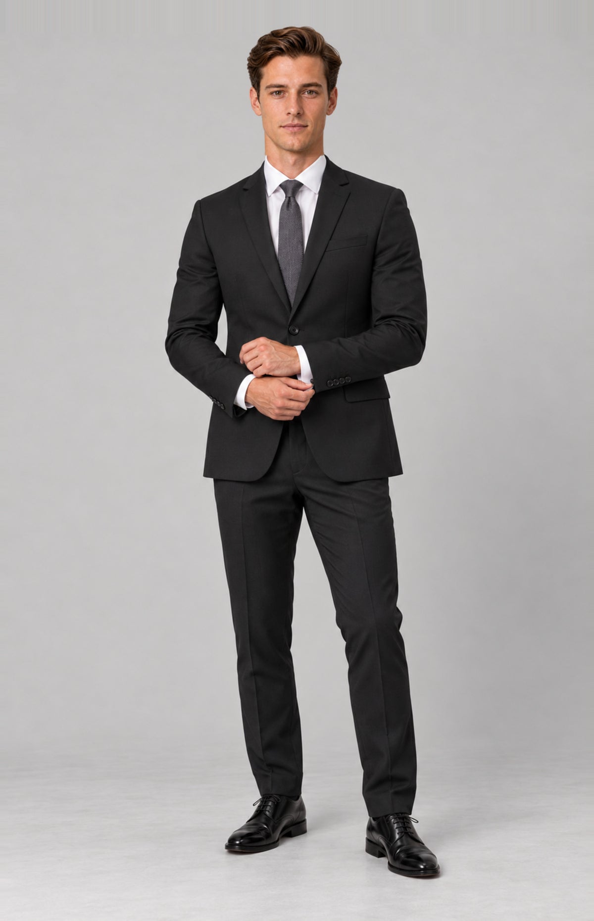 SOGNA T128 Black tailored jacket on M01, full-length cuff-adjusting pose. Jacket only; shirt, tie, trousers and shoes are styling.